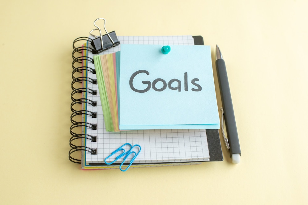 A spiral notebook with a blue sticky note labeled 