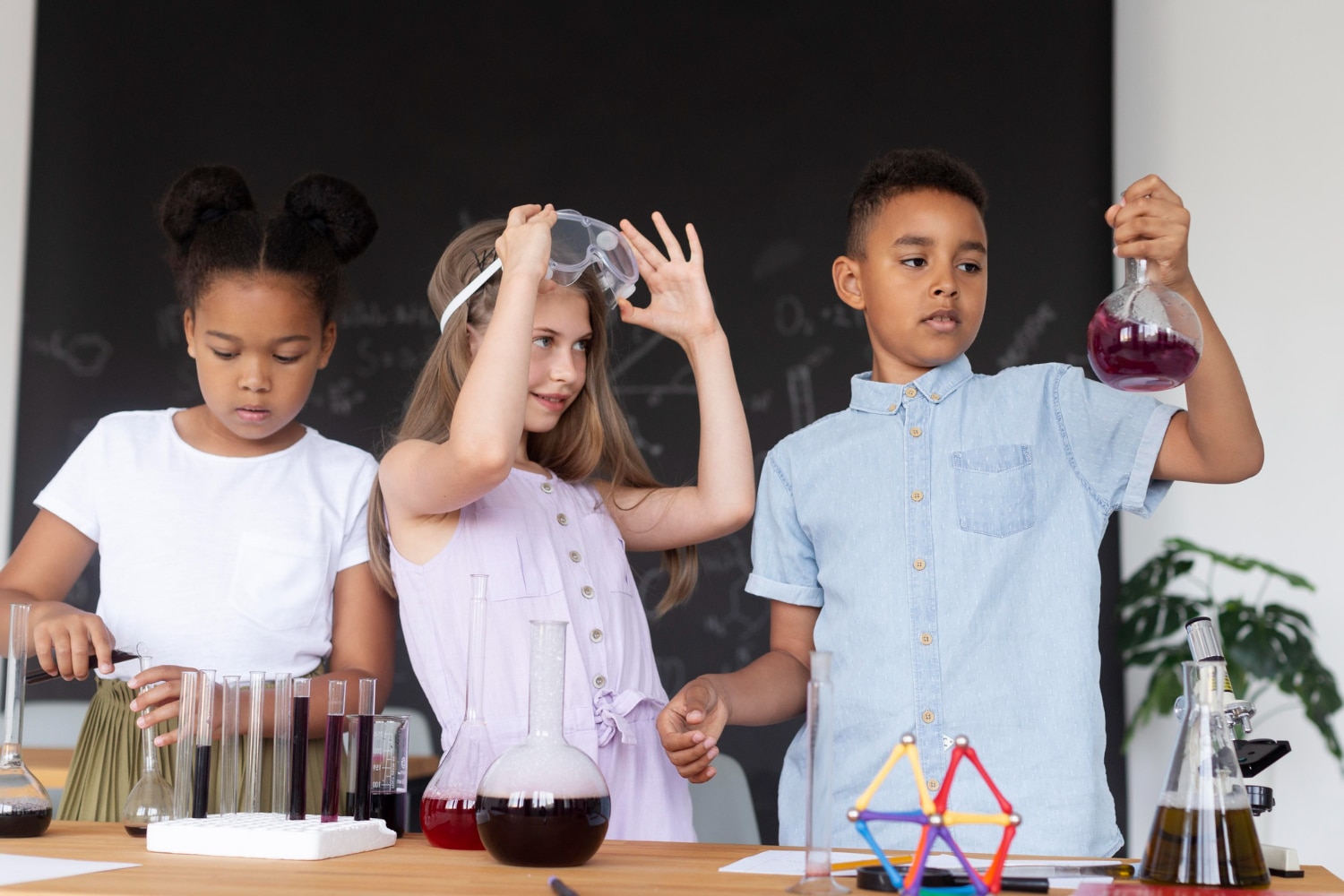 Three children engaging in a science experiment, mixing colorful liquids in glass beakers and test tubes at a laboratory table.