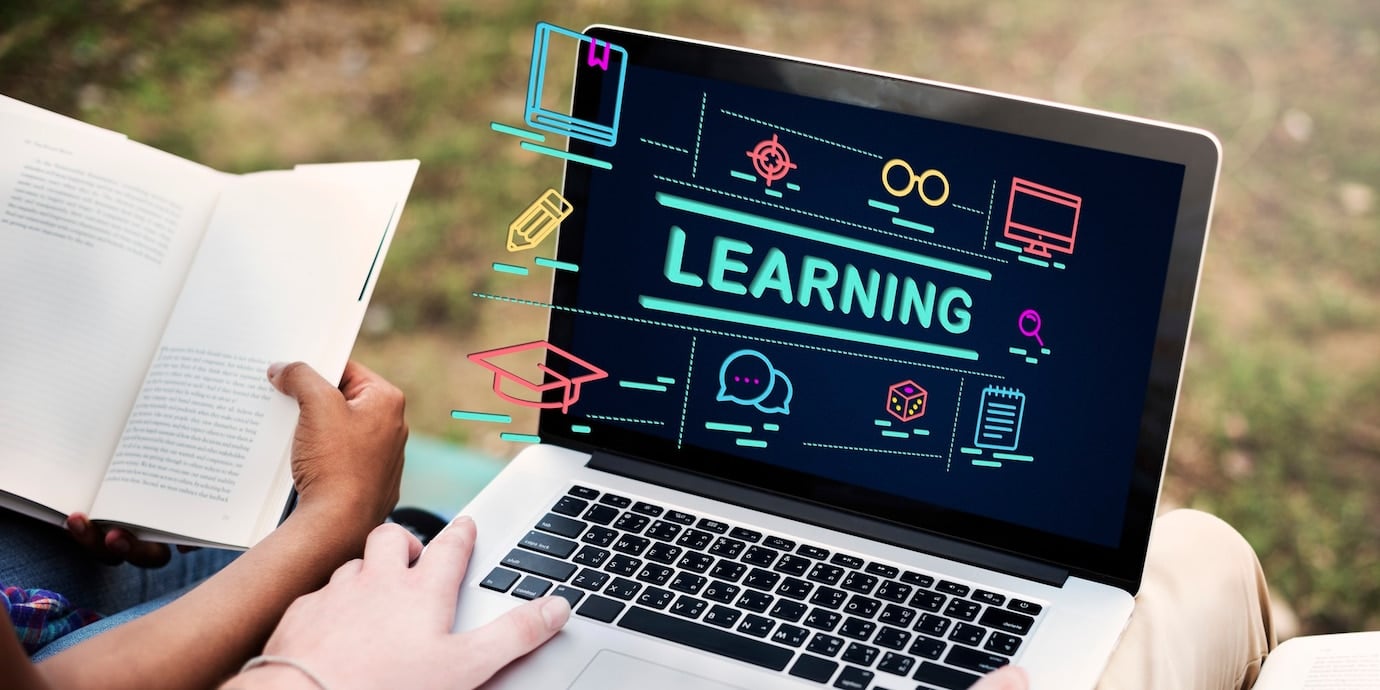 Two people reading books next to a laptop displaying the word LEARNING with colorful educational icons around it.