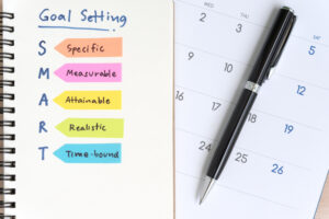 A notebook displaying SMART goal-setting criteria next to a calendar and a pen, emphasizing planning and organization.