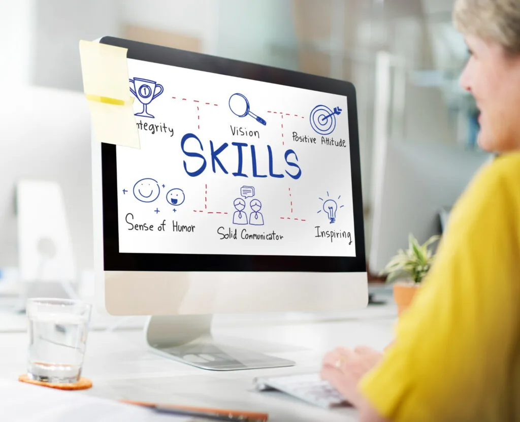 A computer screen displays a colorful diagram labeled Skills, highlighting traits like integrity, vision, and solid communication.