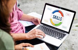 A person typing on a laptop displaying a colorful "Skills" graphic with labels for Research, Ideas, Achievement, and Operation.