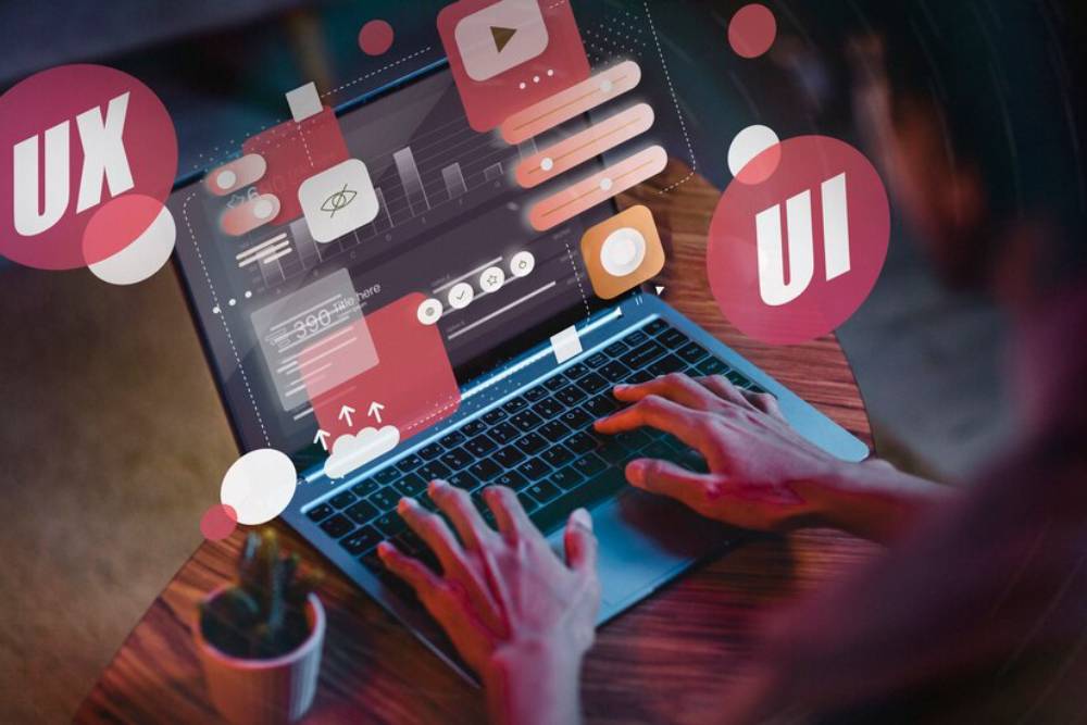 A user interacts with a laptop displaying UI/UX design elements, showcasing digital tools and graphics.